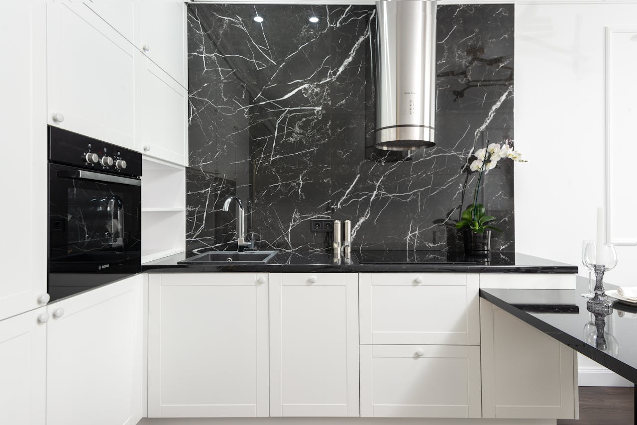 about-02 Sleek contemporary kitchen featuring white cabinets and black marble backsplash for a clean, minimalistic design.